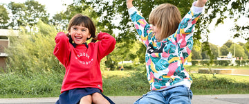 deux enfants dans un skatepark portant des looks streetwear, sweats unisexes oversize colorés en coton bio, chaussettes et baskets de skate motif damier