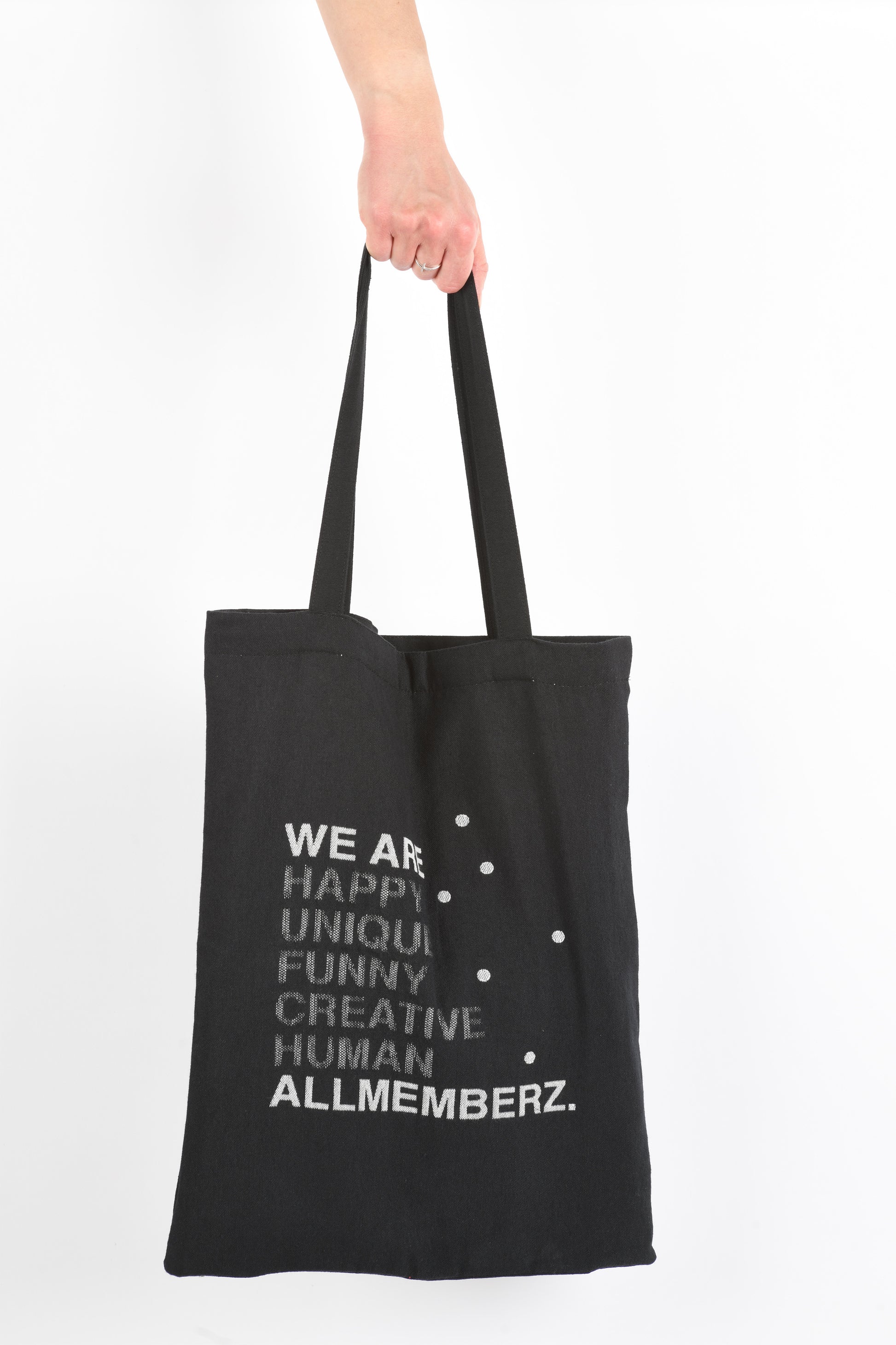 sac en toile tote bag noir Allmemberz, en coton et matériaux recyclés, fabriqué en France, avec message graphique, tenu à la main